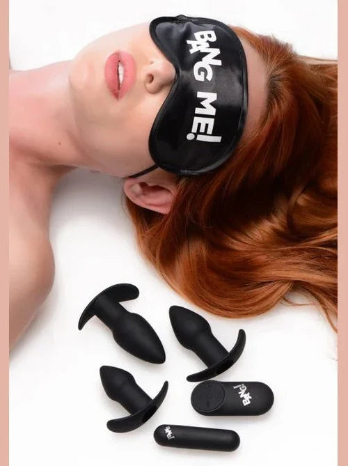 Person wearing a black 'BANG ME!' eye mask with various black objects on a white background
