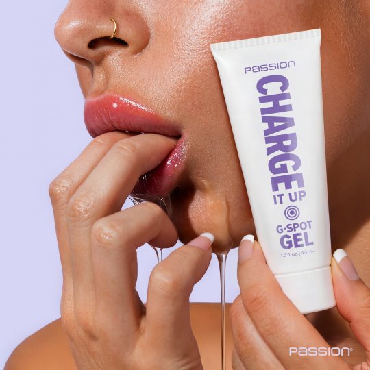 Tube of 'Passion Charge It Up G-Spot Gel' being squeezed with a close-up of lips and hands.