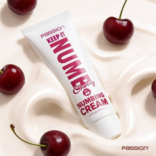 Tube of 'Passion Keep It Nume' numbing cream surrounded by cherries on a light background
