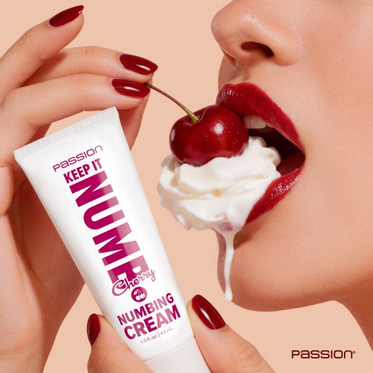 Person holding a tube of numbing cream with a cherry and whipped cream, against a beige background.