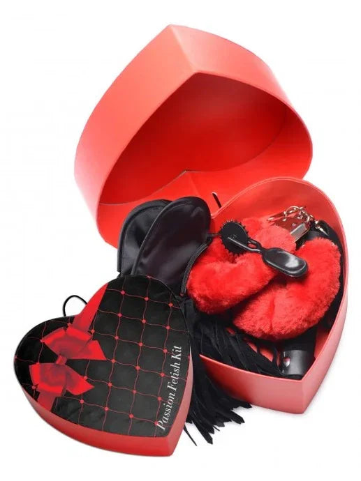 Red heart-shaped box containing a passion fantasy kit on a white background