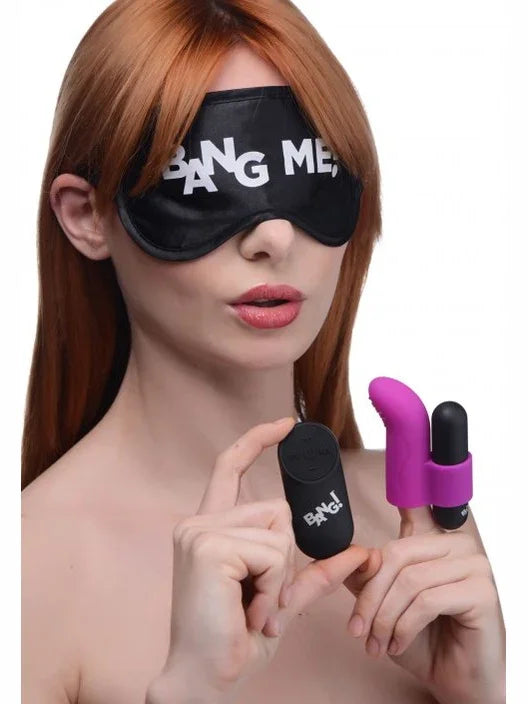 Woman wearing a black eye mask with text, holding two small toys, one black and one purple.
