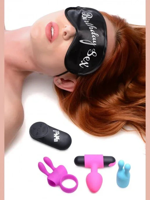 Woman wearing a black 'Birthday Girl' sleep mask with accessories on a white background