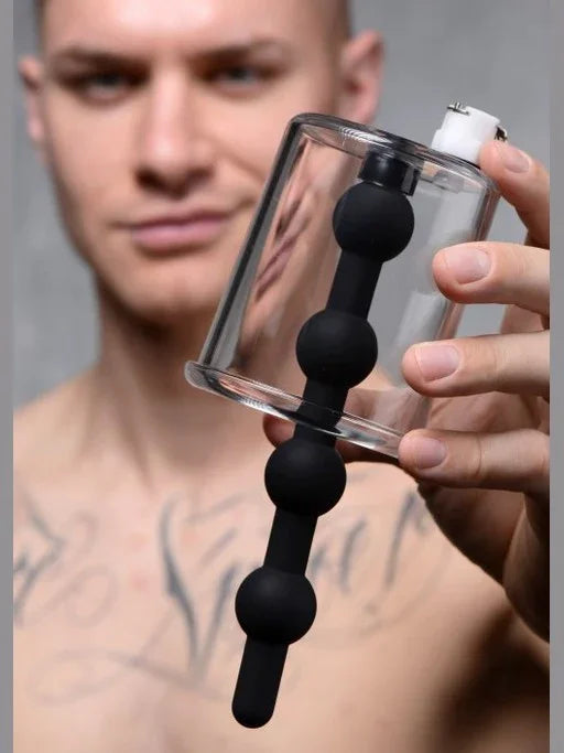 Person holding a clear glass container with black silicone balls against a neutral background