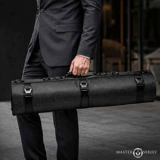 A man in a dark gray suit holds a long, black Master Series instrument case with a textured fabric exterior and multiple black straps and buckles.